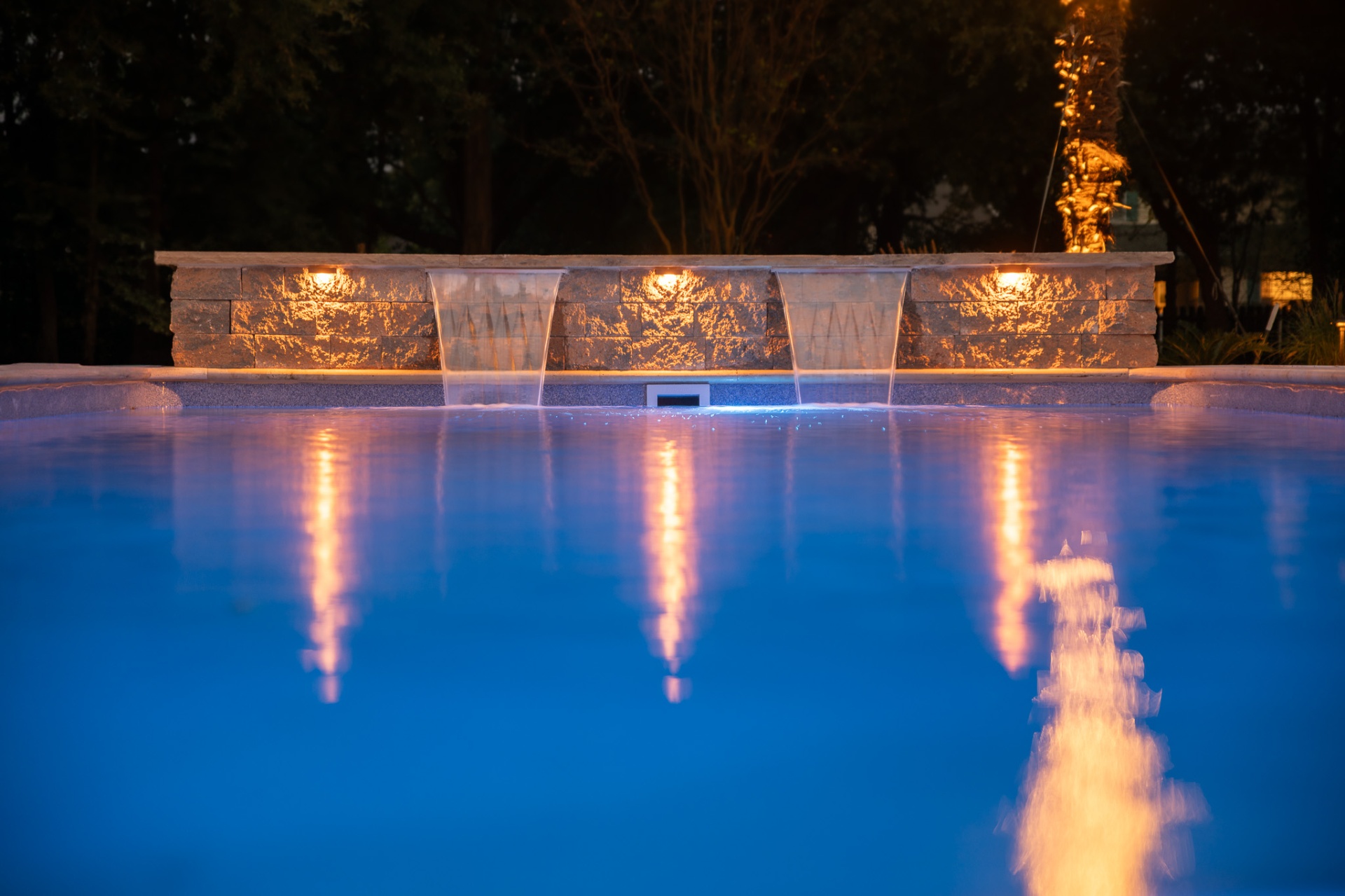 Stacked stone waterfall wall lit at night