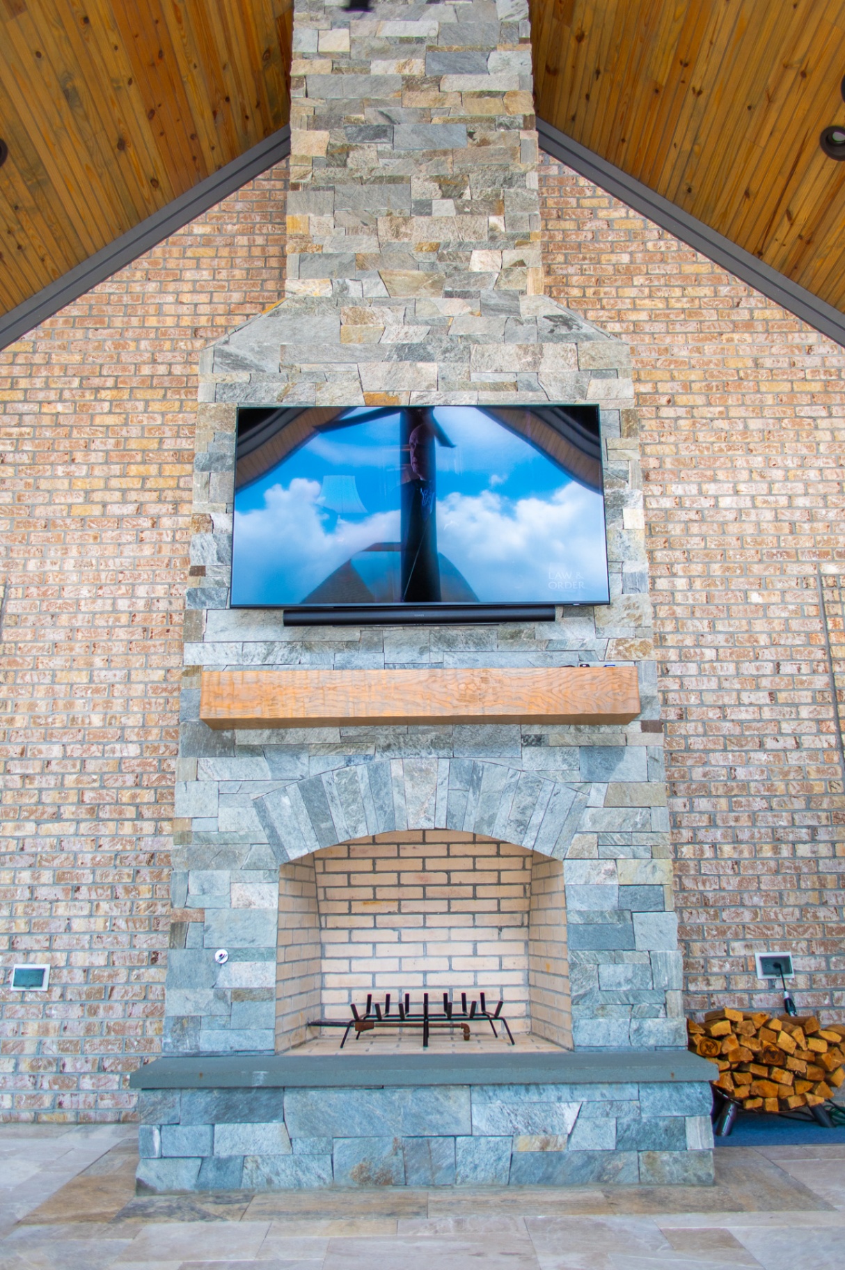 Tall stone fireplace under vaulted wood ceiling