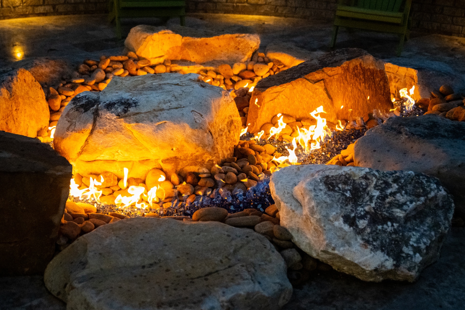 Custom fire pit glowing at dusk beside outdoor seating