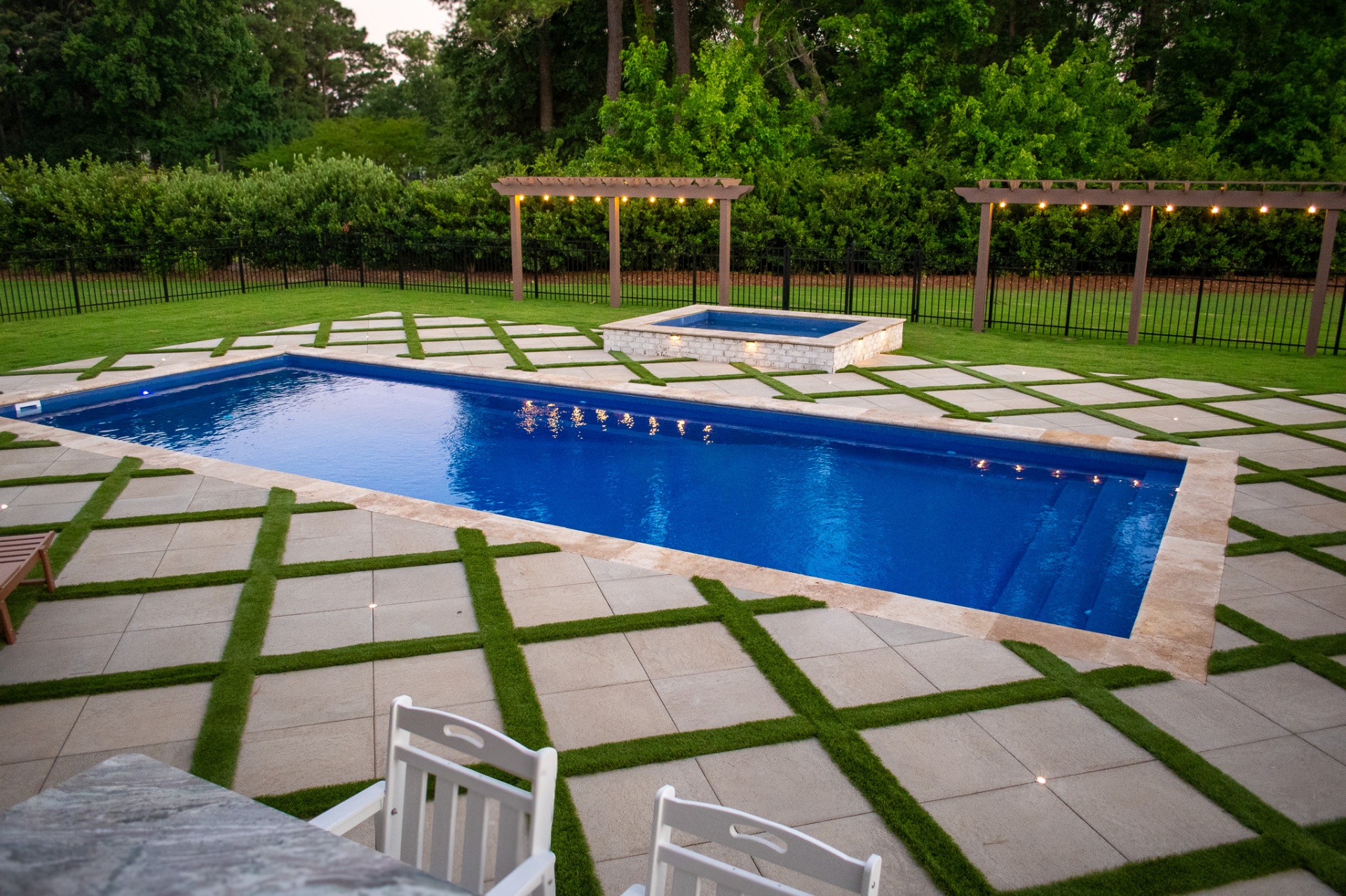 Rectangular pool and spa with lit pergolas